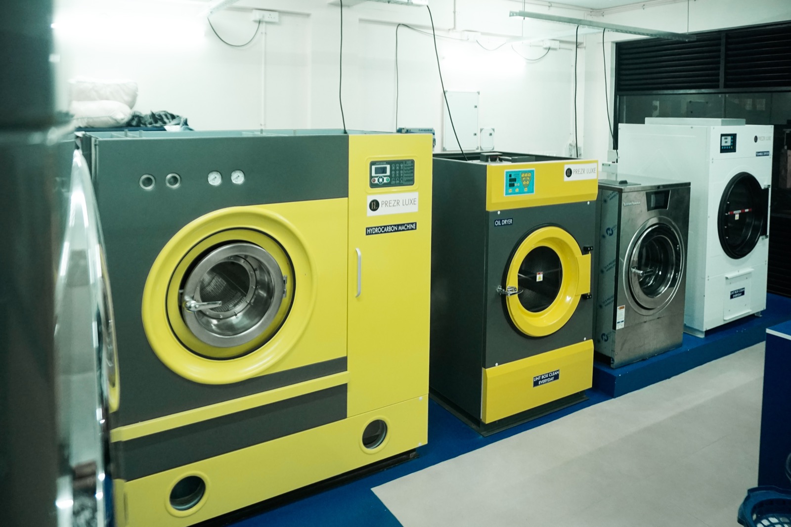The hydrocarbon dry cleaning machine and dryers on the plant floor of the Prezr Luxe studio