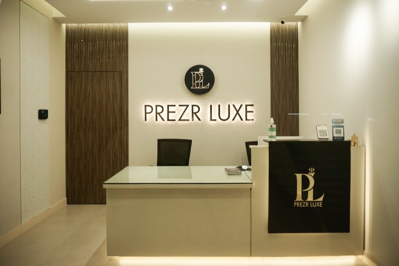 The reception of the Prezr Luxe studio, with the backlit monogram behind the counter