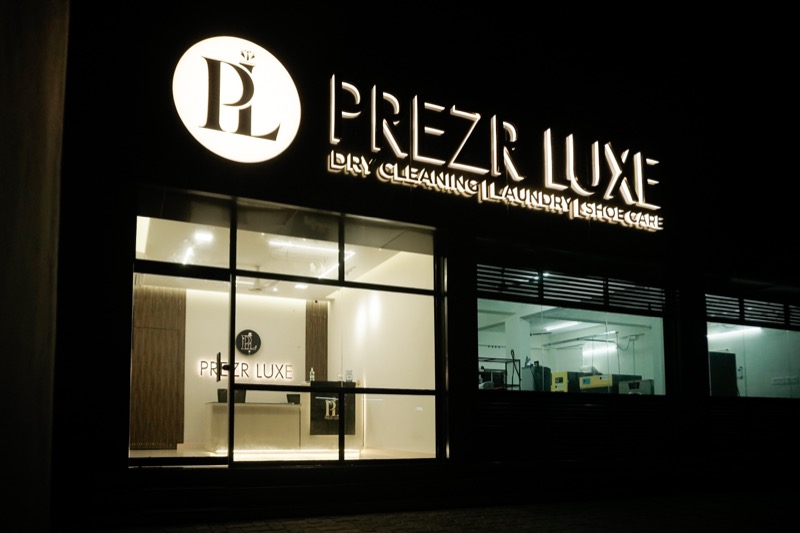 The Prezr Luxe storefront at night with the signage lit